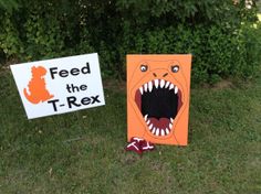 two cardboard signs that say feed the t - rex and feed the cat with their mouths