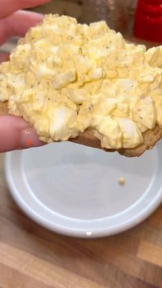 a person holding up a piece of bread with eggs on it