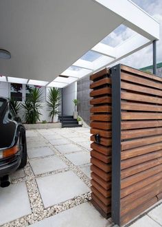 a car is parked in front of a modern house with wood slats on the side