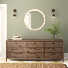 a wooden dresser sitting in front of a mirror on the wall next to a potted plant