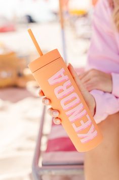 a woman holding a pink and orange drink in her hand with the word kentucky printed on it