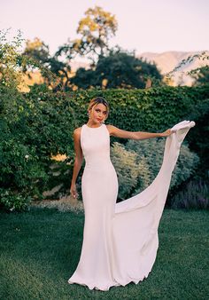 a woman in a white dress is standing on the grass