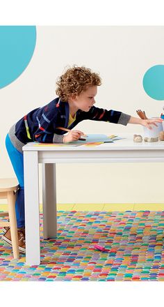 a young boy is sitting at a table with his hands on the paper and drawing