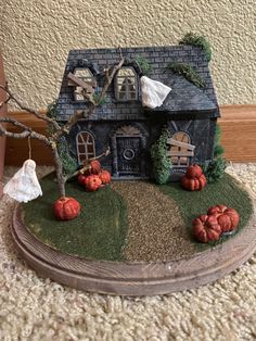 a fake house with pumpkins and trees on the ground