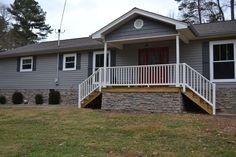 a gray house with white railings and steps leading up to the front door area