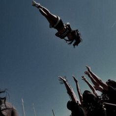 a group of people reaching up into the air to catch a frisbee