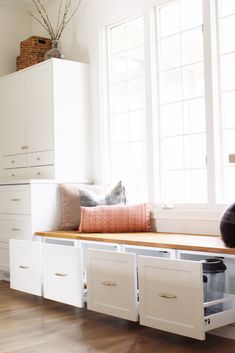 a window seat with storage underneath it in a room filled with white cabinets and drawers