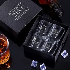 four glasses in a gift box next to some ice cubes and an empty bottle