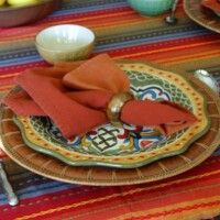 the table is set with plates, bowls and napkins on it's placemats