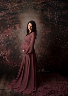 a pregnant woman in a long dress poses for the camera with her hands on her hips