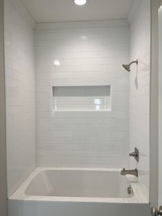 a white bath tub sitting inside of a bathroom next to a shower head and faucet