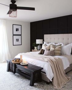 An upholstered headboard leans against a Tricorn Black accent wall in this modern bedroom. This rich color gives this bedroom the perfect amount of moody contrast fit for a modern farmhouse bedroom. A black wood bench at the foot of the bed plays off of the dark color accent...   Image: myhousefromscratch