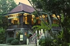 an old house is lit up at night in the forest with stairs leading to it