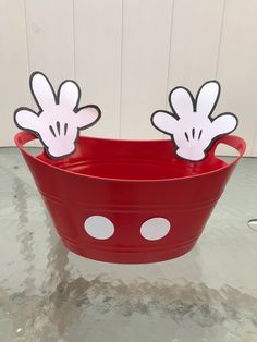 a red bucket with mickey mouse cutouts on the top and two minnie mouse ears sticking out of it