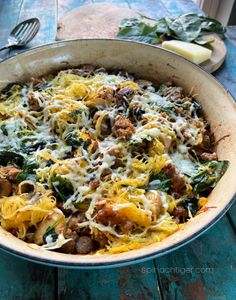 an italian sausage casserole in a pan with cheese and spinach on top