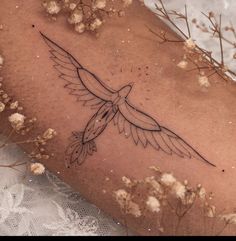 a tattoo on the leg of a woman with flowers in front of her and an image of a bird flying