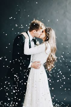 a bride and groom kissing in front of confetti