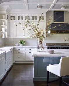 a kitchen with white cabinets and marble counter tops