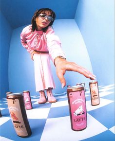 a woman in pink shirt and glasses reaching for canisters