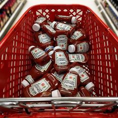 a red shopping cart filled with lots of ketchup