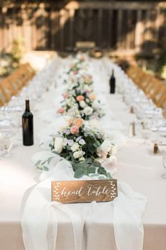 a long table with white linens and flowers