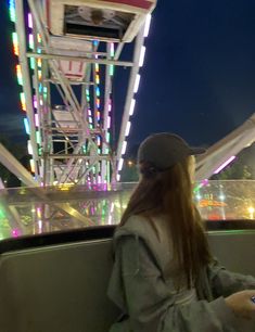 a woman sitting in front of a ferris wheel at night