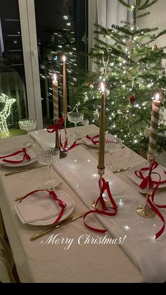 a christmas table setting with candles and place settings