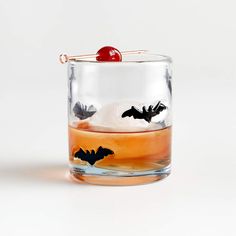 a glass filled with liquid and a cherry on the top in front of a white background