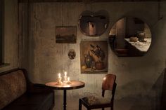 two candles are lit on a small table in the corner of a dimly lit room