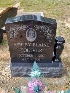 the headstone of ashley elane toliver is surrounded by flowers and plants