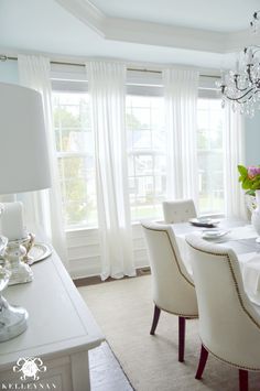 a dining room table with white chairs and chandelier