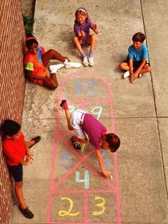 children drawing numbers on the sidewalk with chalk