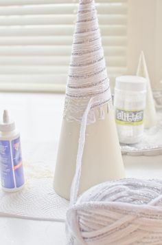 a white christmas tree sitting on top of a table next to twine of yarn