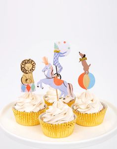 three cupcakes with white frosting and decorations on top are sitting on a plate