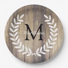 a wooden plate with the letter m on it and an olive branch in the middle