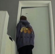 a person standing in front of an open door wearing a purple jacket with bananas on it