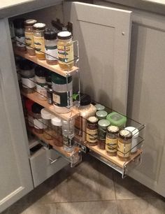 an open cabinet in a kitchen filled with spices