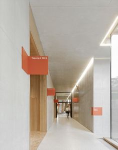 an empty hallway with orange and white signs on the walls, along with two people walking down one side