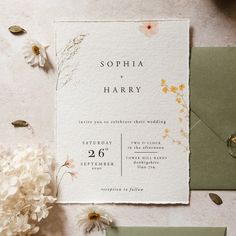 the wedding stationery is displayed with flowers and greenery