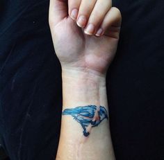 a person with a blue bird tattoo on their wrist holding up her hand to the camera