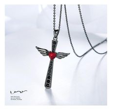 The center piece for this gothic style pendant is the red ruby heart crystal. The red crystal is set amongst a full column of black Swarovski crystals that span the entire vertical beam of this cross. The horizontal beam of the cross is formed by the angelic wings that project from the heart itself. It's beautifully crafted, with clear lines separating the 4-feathered wings. This elegant piece from Innovato Design is made from a gunmetal black-plated copper alloy material. The crystals of the pendant are high grade Swarovski Crystals. This piece comes with an 18" chain link necklace with a 5 cm extender chain. The pendant measures 1.61 in x 0.96 in.  Product Highlights    Made from durable Copper Material  Gunmetal Black-plated Finish  Embellished with Swarovski Crystals  Chain Link Neckla Gothic Black Cross Necklace Gift, Black Gothic Necklace For Valentine's Day, Gothic Black Necklace For Valentine's Day, Black Spiritual Jewelry For Valentine's Day, Spiritual Black Jewelry For Valentine's Day, Angelic Wings, Feathered Wings, Wood Inlay Rings, Dragon Star