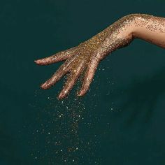 a woman's hand with gold glitter on her body and hands extended out to the side