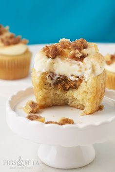 some cupcakes are on a white plate and one is cut in half with a bite taken out