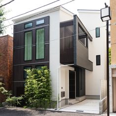 an apartment building with black and white sidings on the front, green shutters on the second floor