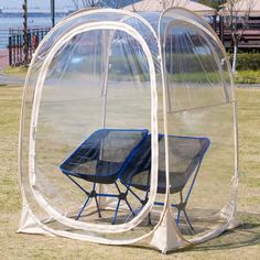 two chairs sit in a clear tent on the grass