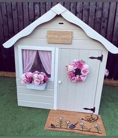 a small doll house with flowers on the door