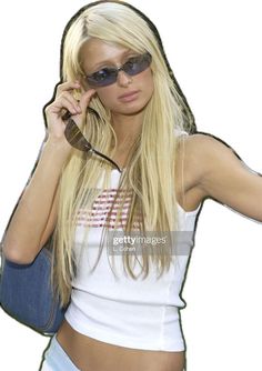 a woman in white shirt and sunglasses holding a cell phone to her ear with both hands