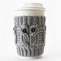 a knitted cup cozying with a coffee cup sleeve and the lid is made to look like an owl's head