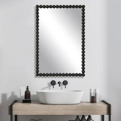 a white sink sitting under a mirror on top of a wooden table next to a wall