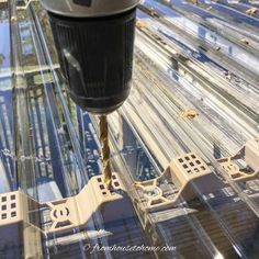 a drill is being used on the top of a glass table with multiple tracks in it